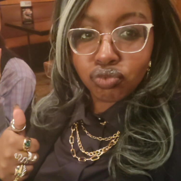 glammed up me a selfie of me at my high school graduation dinner. my hair is salt and pepper, curly at the ends. I'm wearing a black button-down and gold jewelry, and i'm sticking a thumb up and pouting playfully.